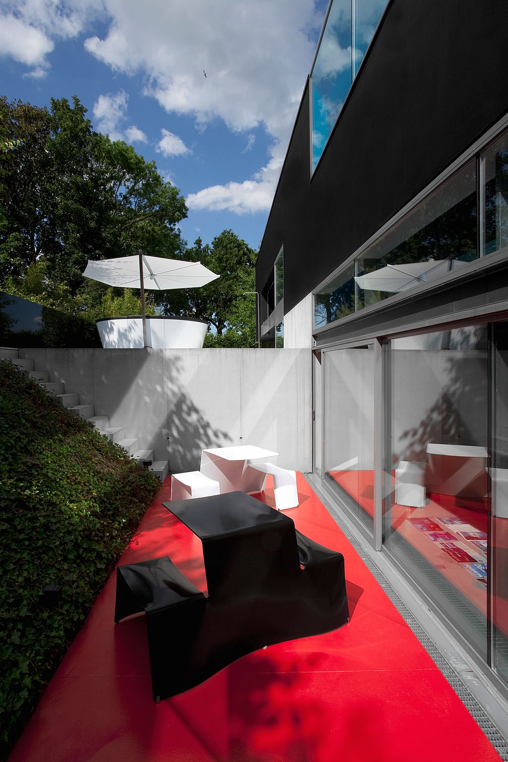 Assises sur une terrasse rouge encadrées par une architecture moderne