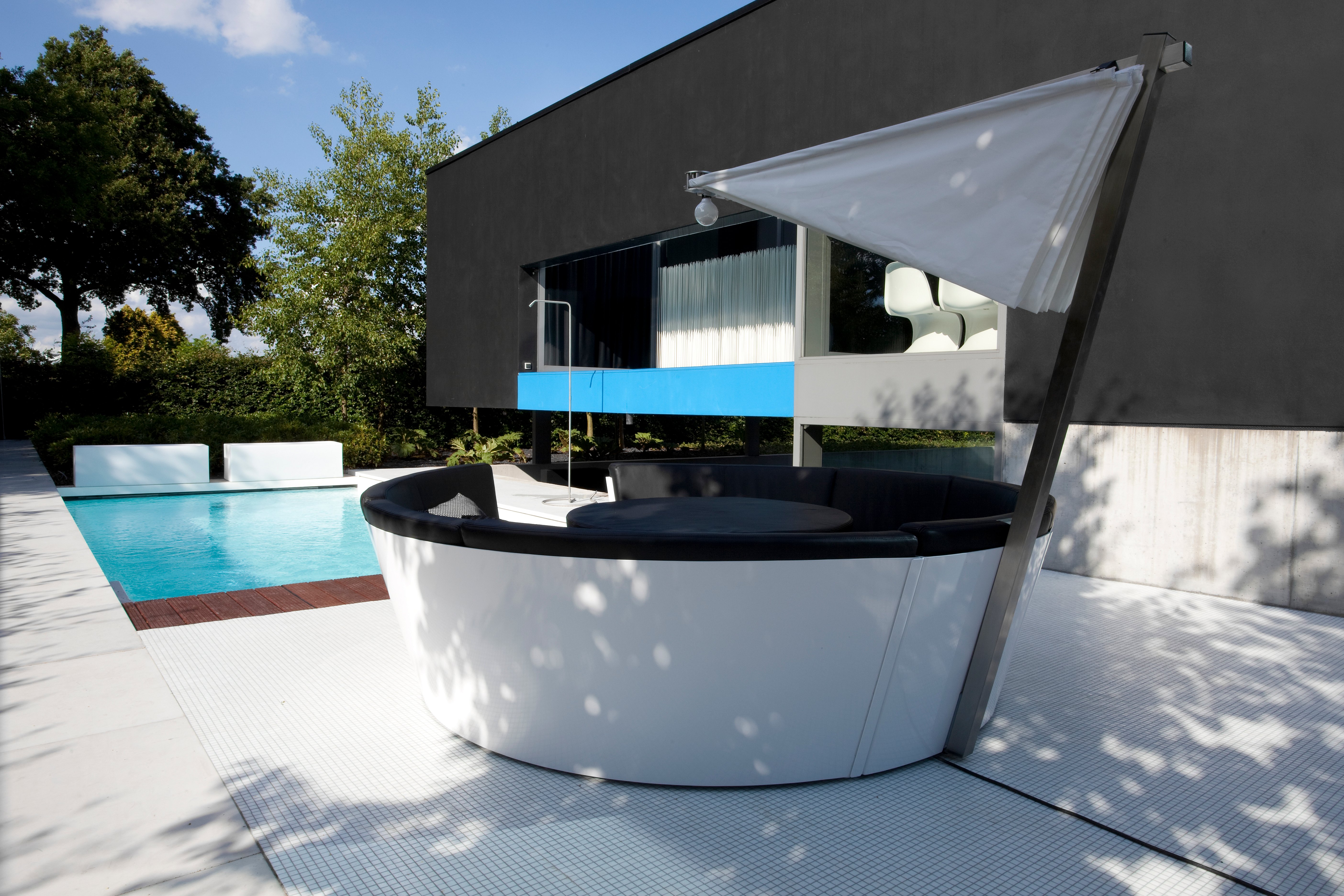 Canapé circulaire Kosmos avec ombrage intégré au bord d'une piscine moderne