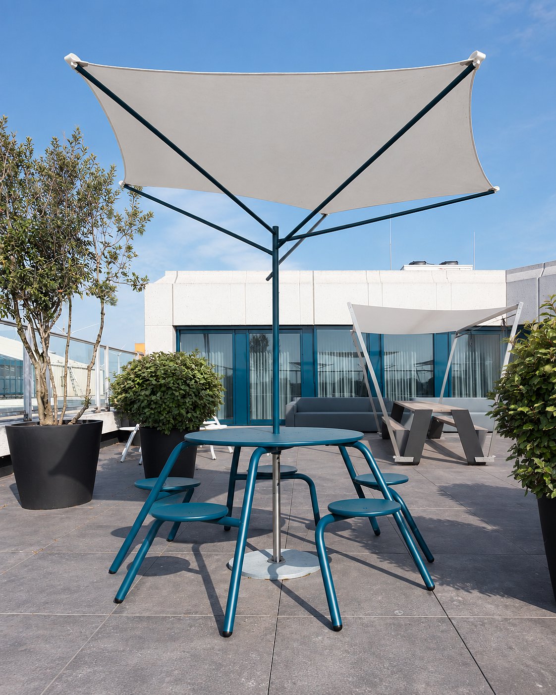 Table Virus bleue avec parasol Acacia sur un toit-terrasse de bureau moderne