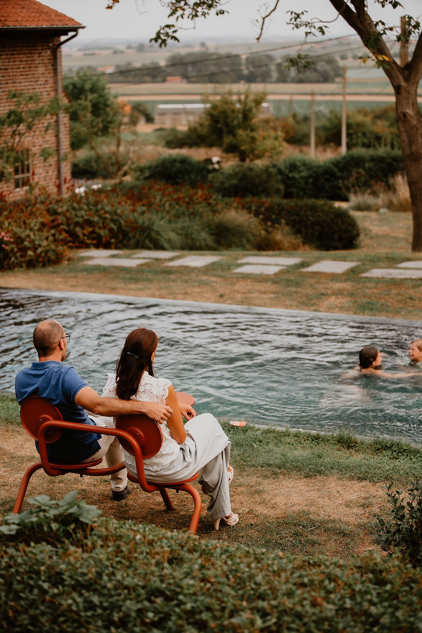 Couple relaxing on a Bistroo seat beside the swimming pool at a Belgian farmhouse