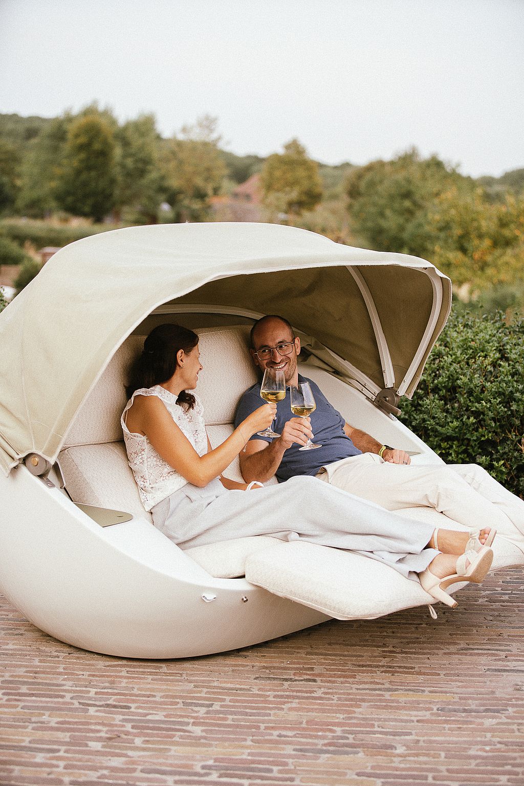 Couple enjoying drinks together in a Cabrio sofa with the soft top open