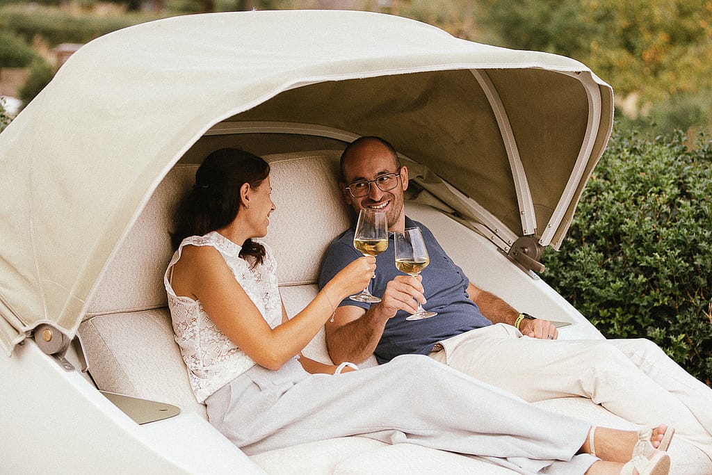 Couple with drinks in the Cabrio with the soft top open, on a brick terrace