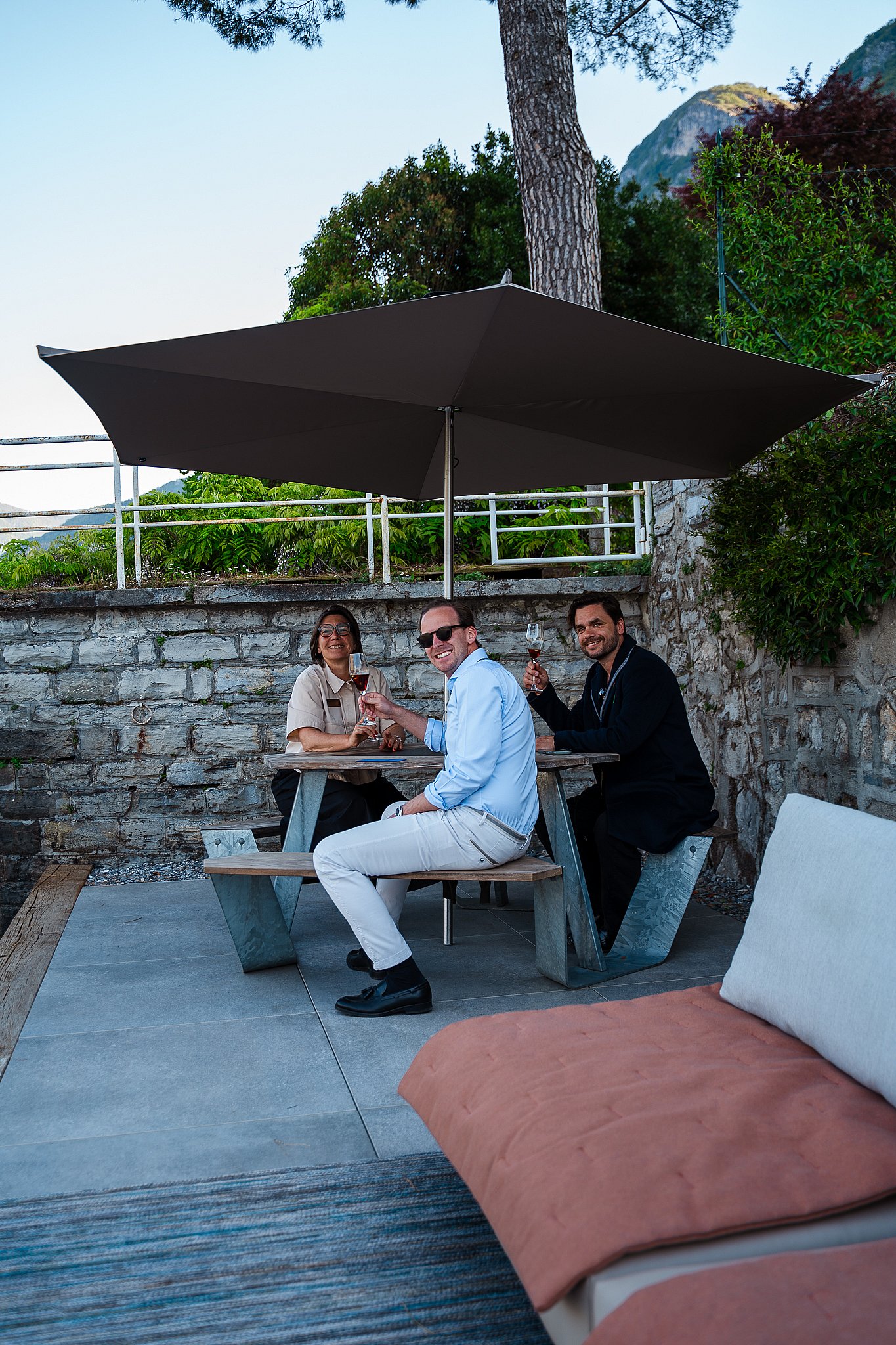 Guests sitting at the Extremis Anker picnic table under a shade on the lakeside terrace