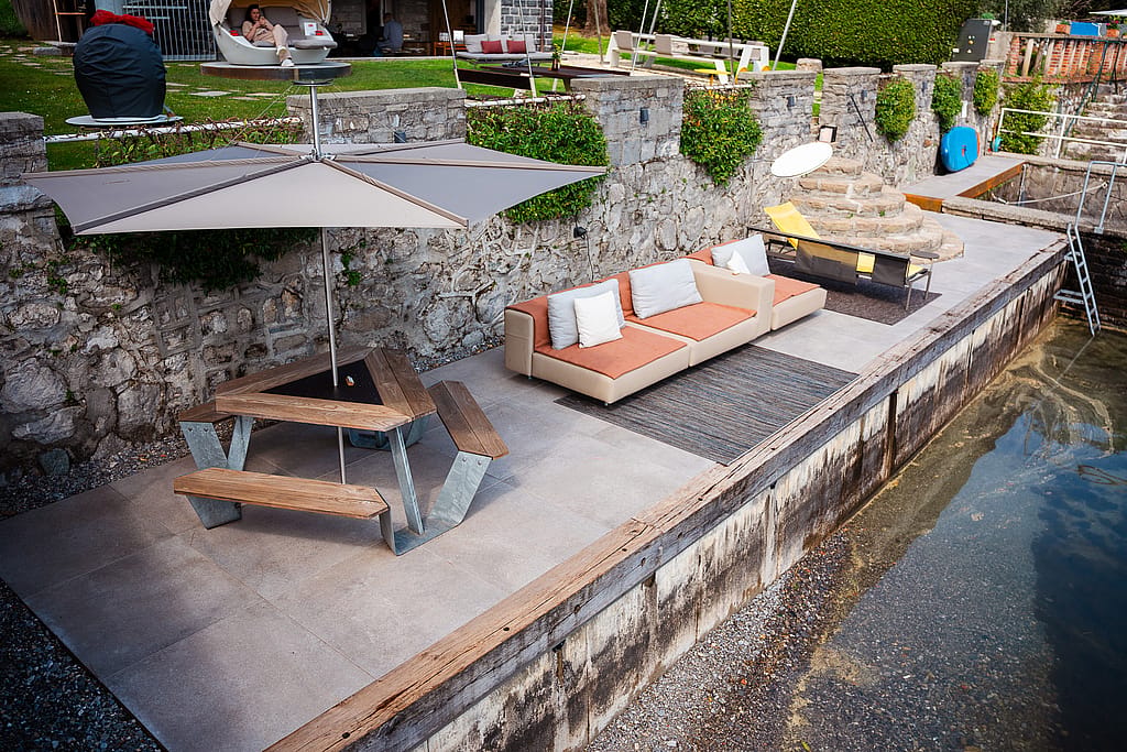 Extremis Anker picnic table and Walrus sofa on a waterfront terrace at Lake Como