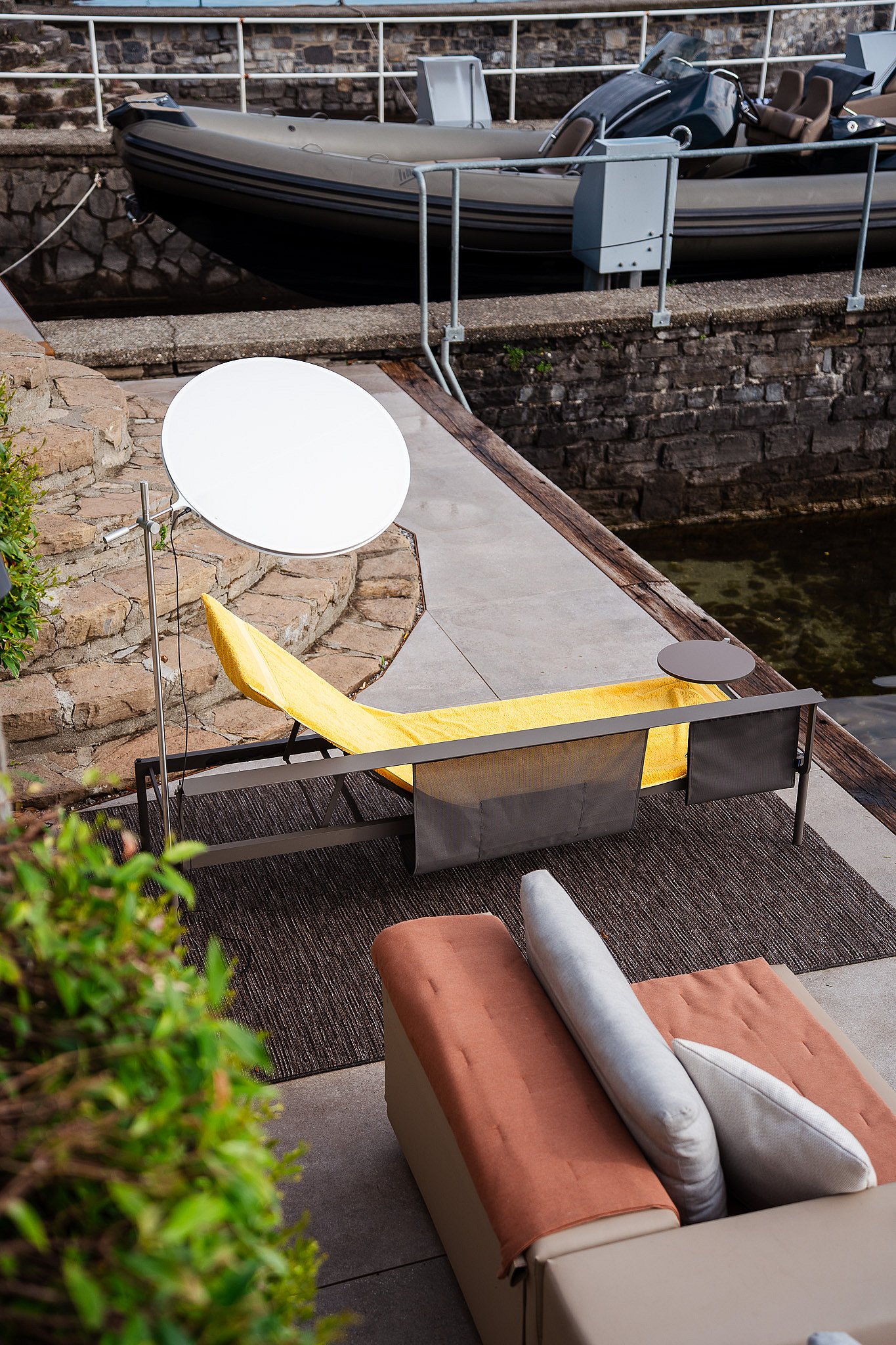 Extremis Sol+Luna sunbed with its round LED sunshade beside the water