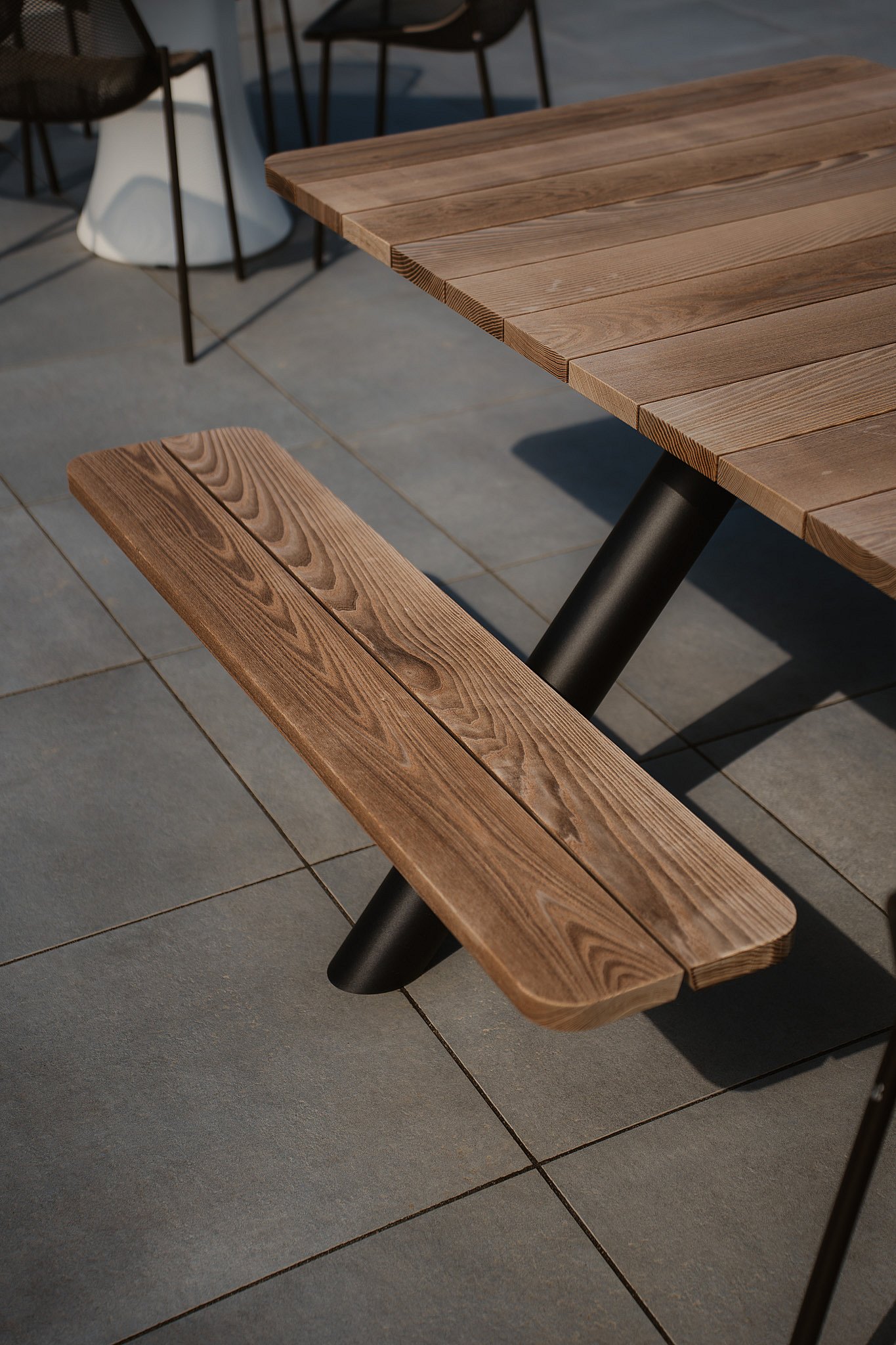 Close-up of the wooden top and bench of the Extremis Panigiri outdoor dining table
