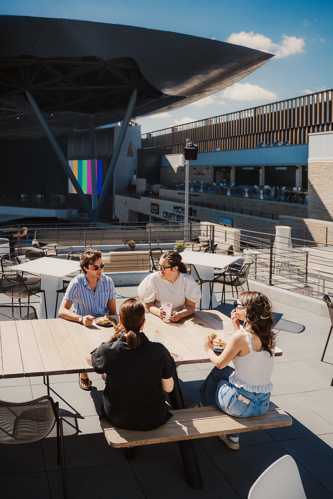 Group of guests at an Extremis Panigiri outdoor dining table on the terrace at Acrisure Amphitheater