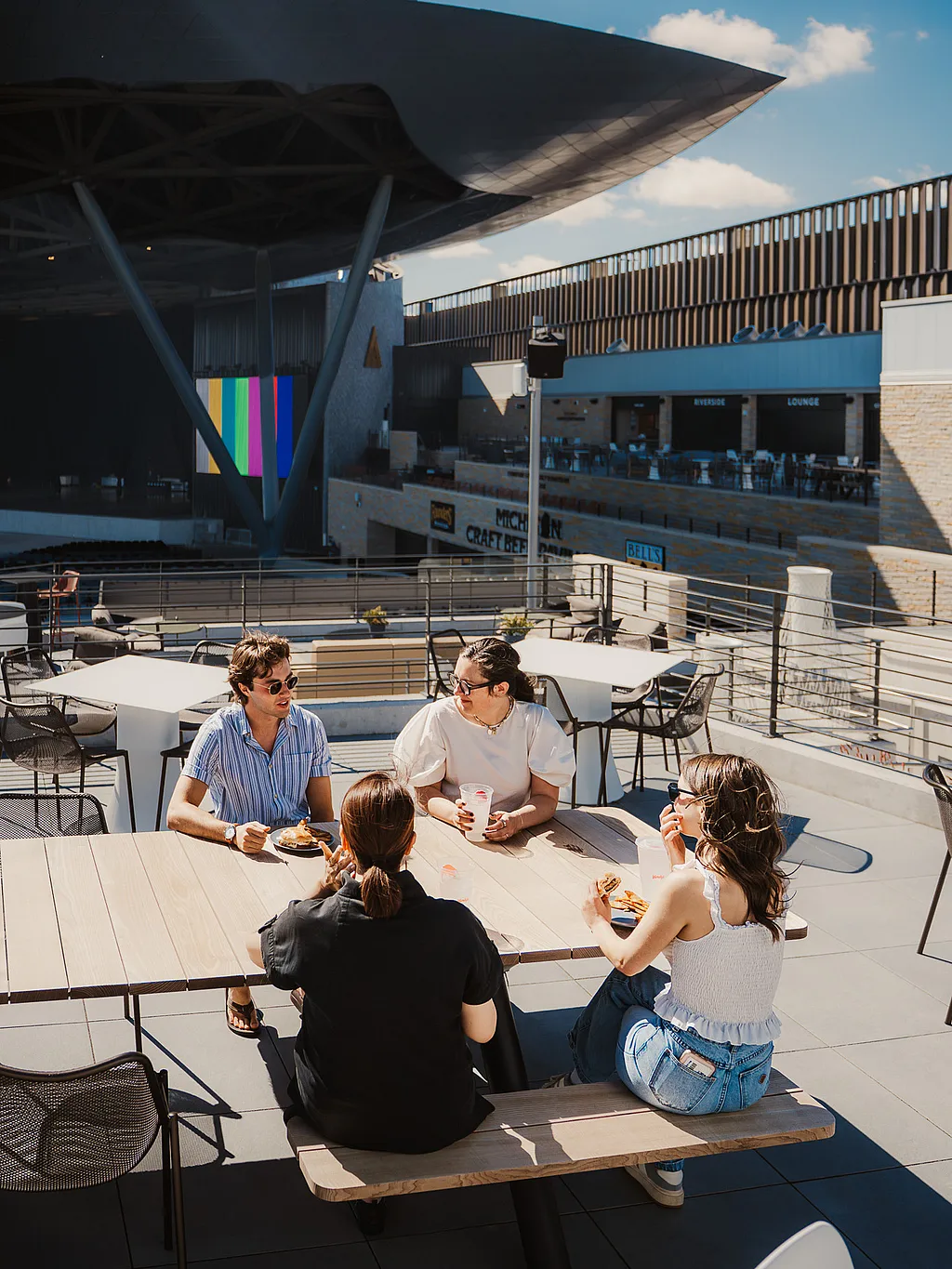 Group of guests at an Extremis Panigiri outdoor dining table on the terrace at Acrisure Amphitheater