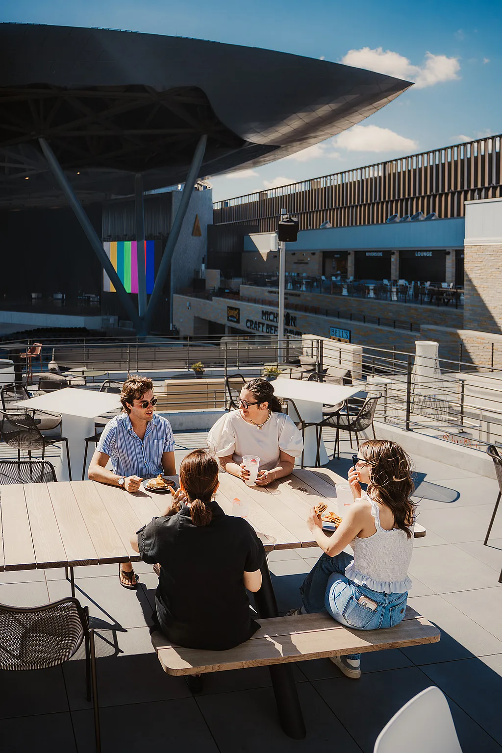 Group of guests at an Extremis Panigiri outdoor dining table on the terrace at Acrisure Amphitheater