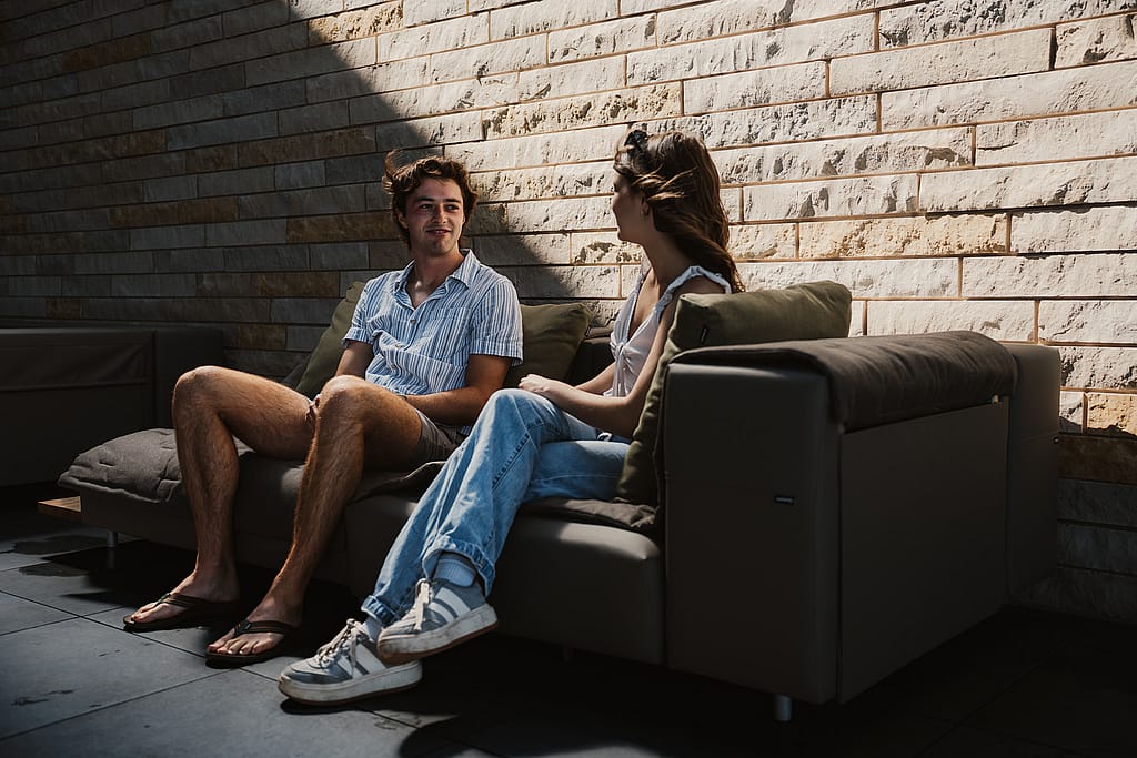 Two guests side by side on an Extremis Walrus outdoor sofa on the Club Terrace