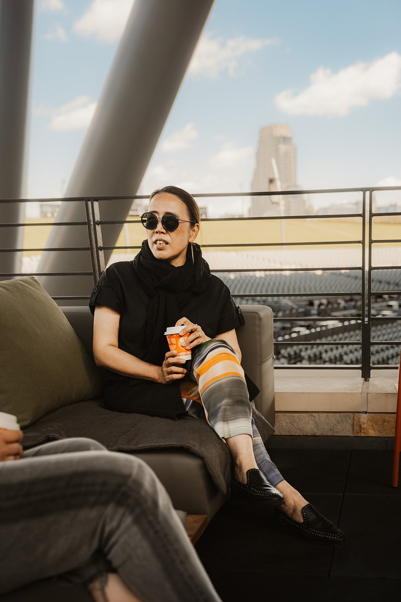 Guest with a drink on an Extremis Walrus outdoor sofa, with the Grand Rapids skyline behind